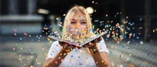 Student Blowing Confetti off of a book